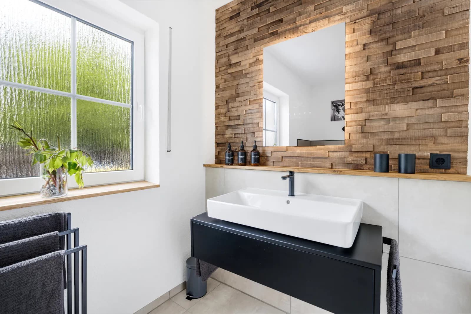 Modernes Badezimmer mit Holzriemchen-Wand, schwarzem Waschtisch und weißem Aufsatzbecken
