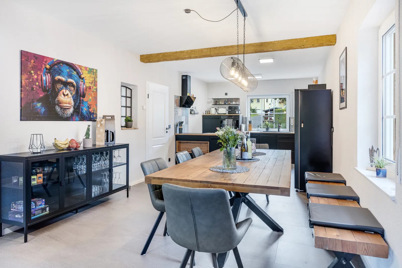 Moderne Wohnküche mit langem Holztisch, schwarzen Vitrinen und Blick in die offene Küche
